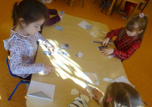 Dzieci układają przy stoliku obrazki z części.
